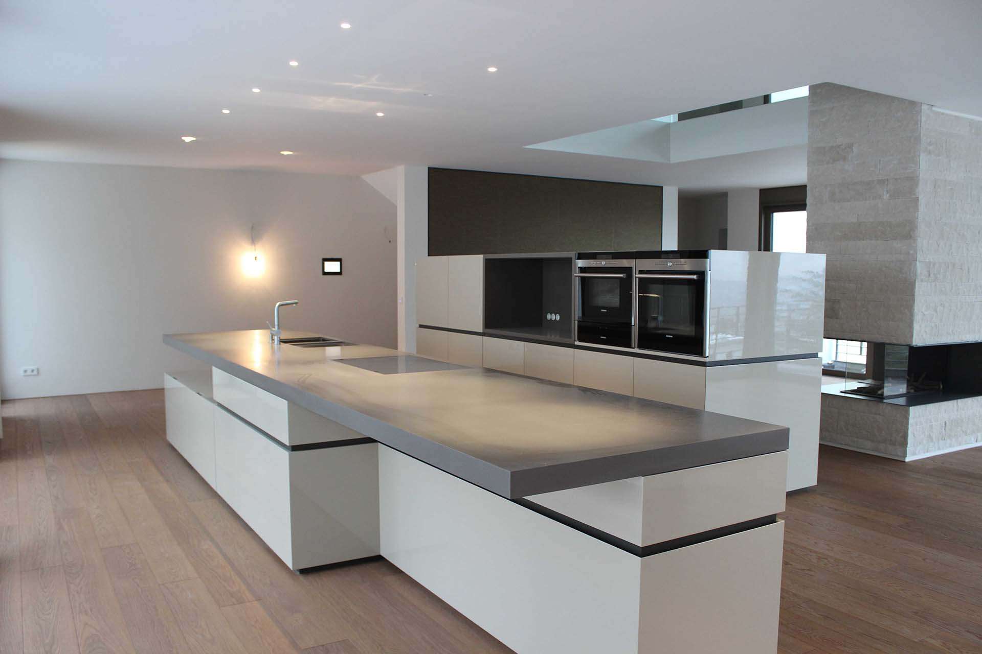 Freistehende Küche mit zwei Blöcken. Massive und dicke Arbeitsplatte in grau. Sitzmöglichkeit bzw. Bar am Küchenblock/Kücheninsel.