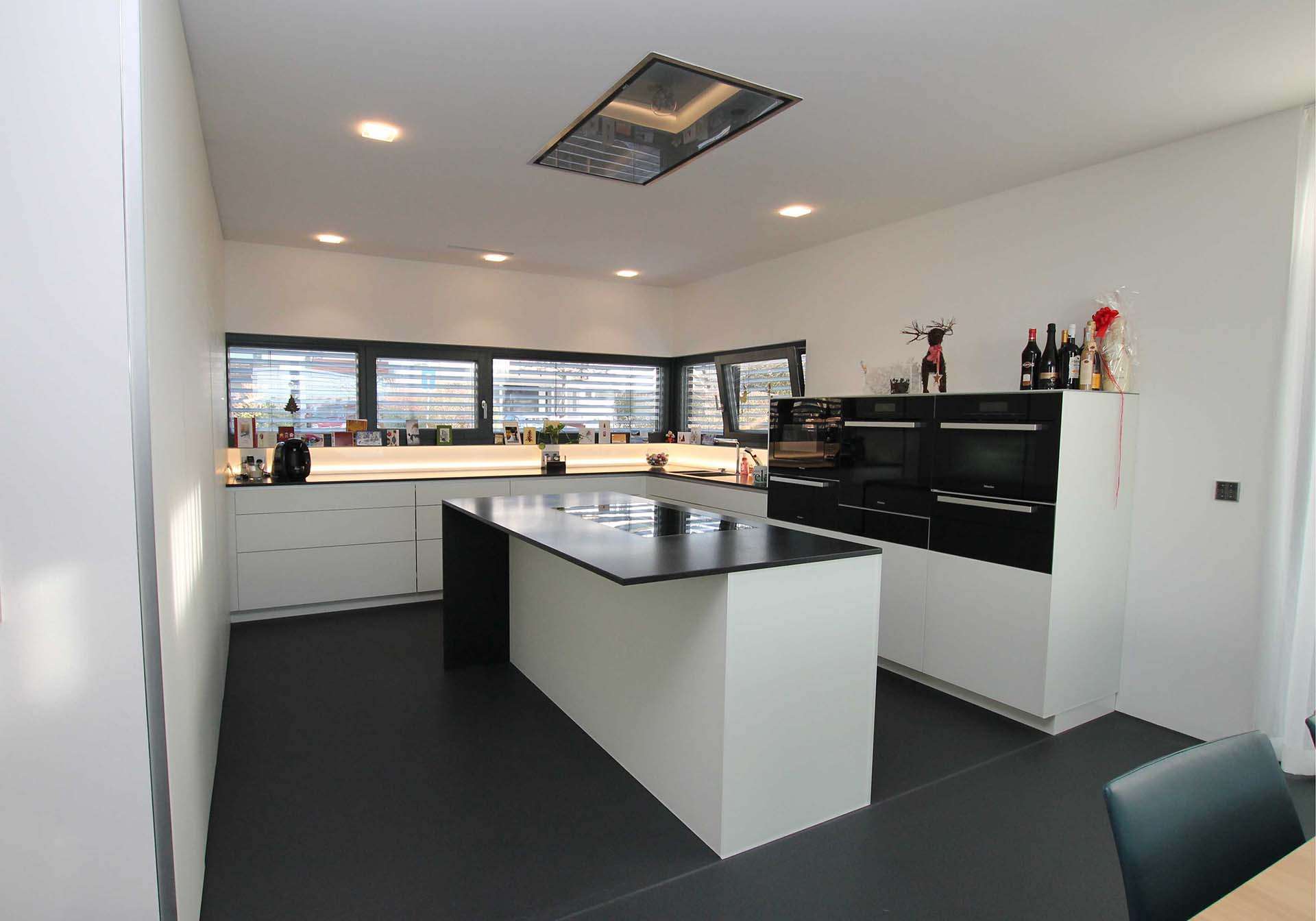 U-förmige Küche mit einer Kücheninsel in der Mitte. Arbeitsfläche aus schwarzem Granit. Die integrierten Küchengeräte alle aus einer Serie in schwarz.