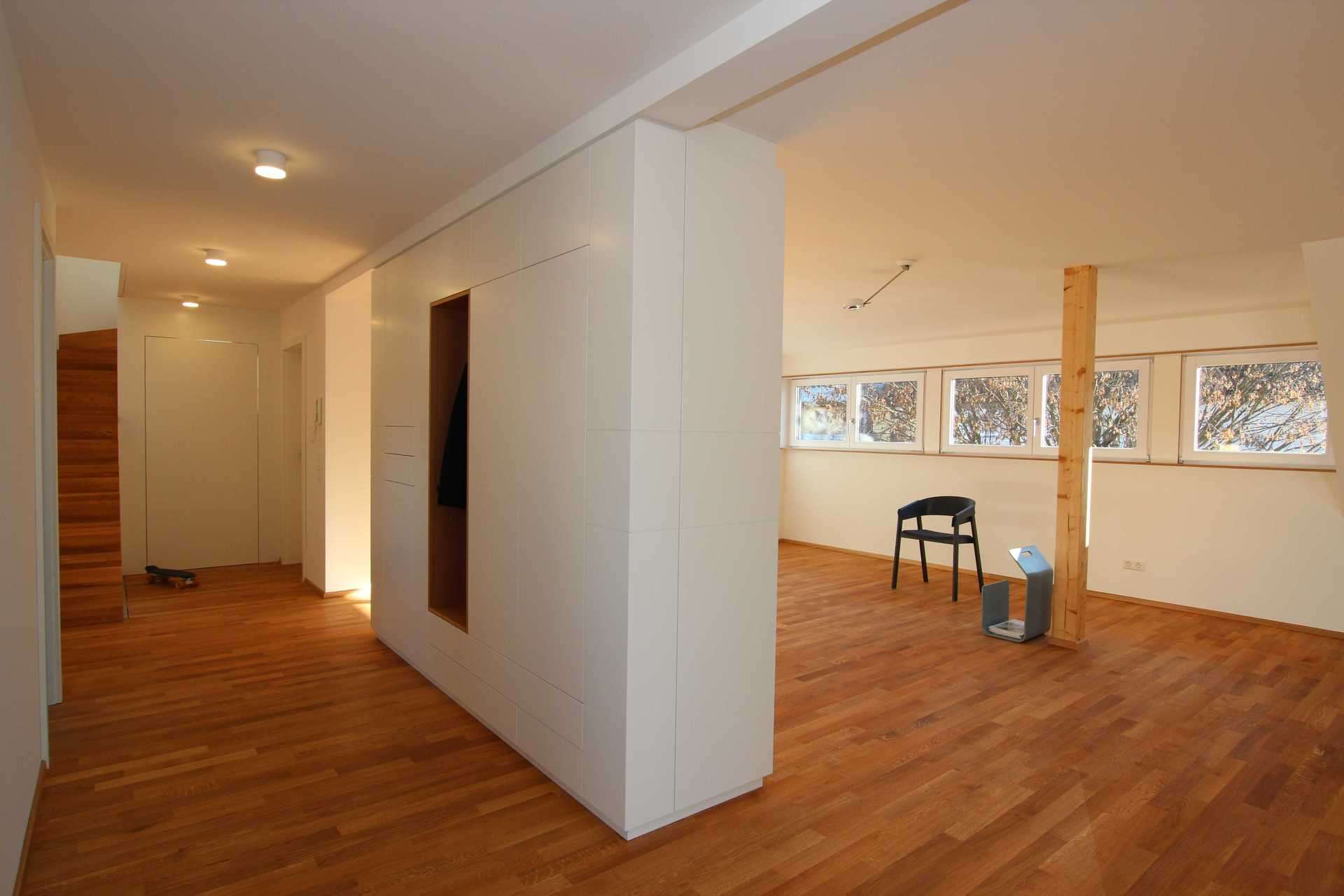 Deckenhoher Schrank als Raumtrenner, der den Eingangsbereich vom Wohnzimmer trennt. Offene Garderobe integriert.