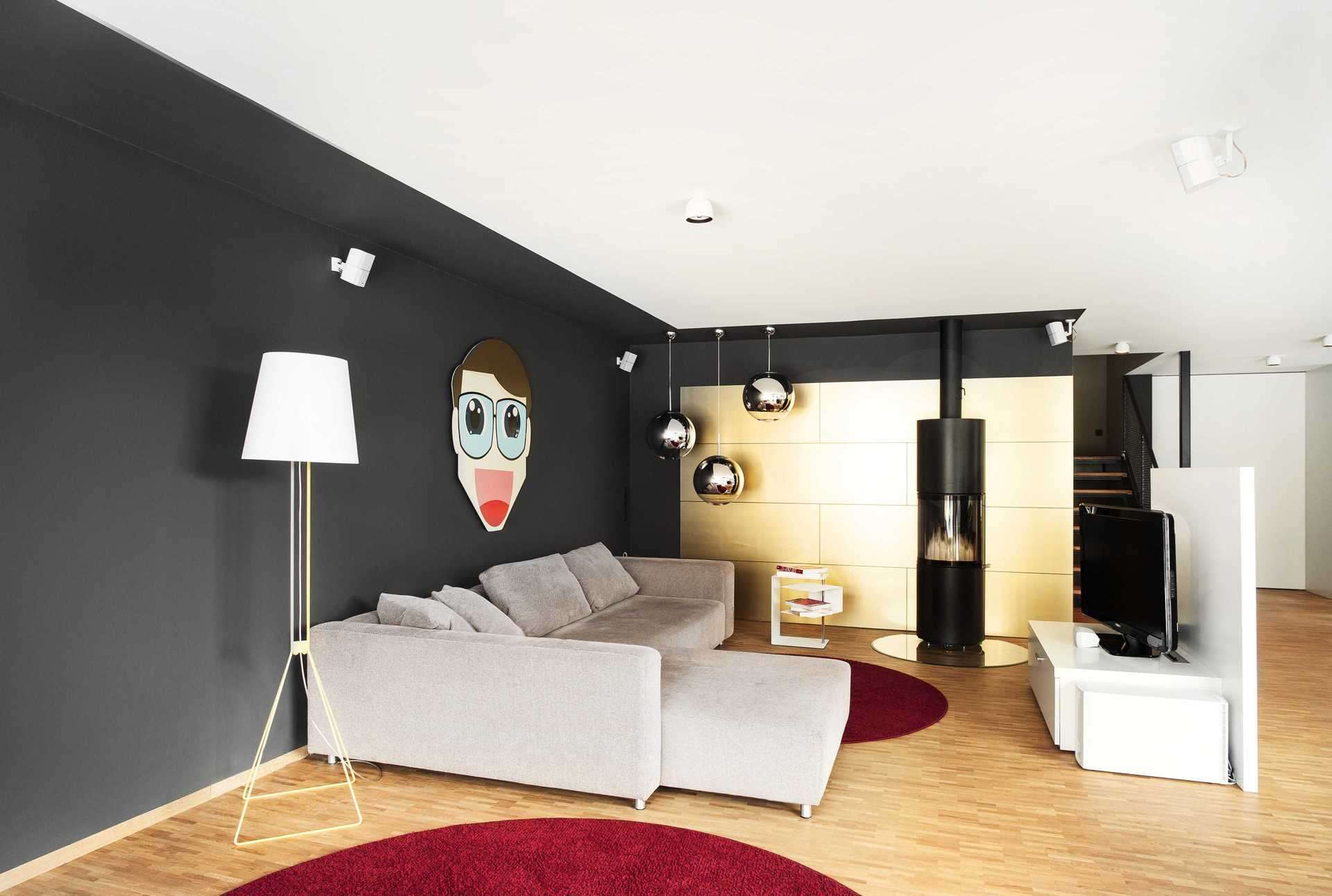 Wandverkleidung in Wohnzimmer in gold, als Rückwand des Kamins. Freistehendes Fernsehmöbel in Weiß mit Rückwand zum Essbereich.