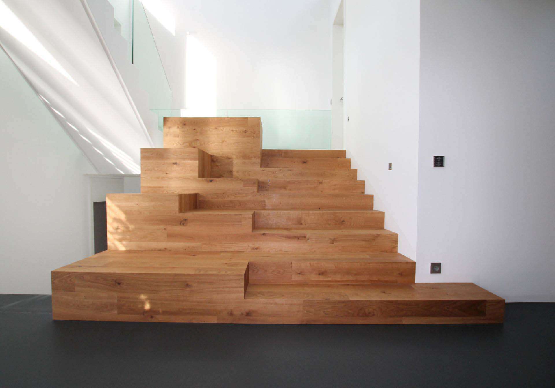 Sehr breite Treppe aus Massivholz auf verschiedenen Ebenen mit Sitzmöglichkeiten.